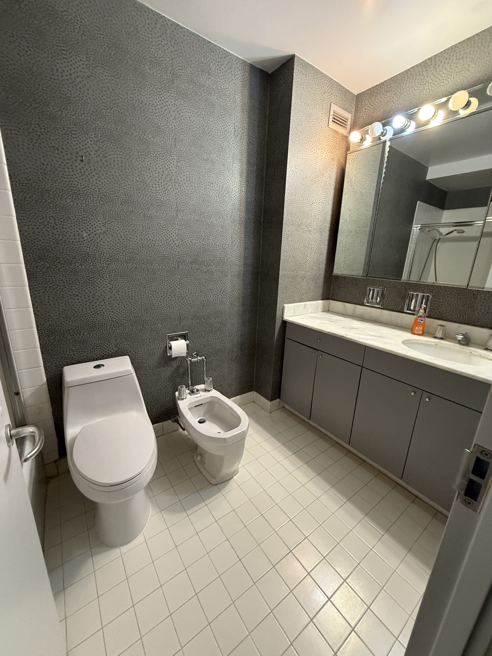 Bathroom with gray cabinets, a marble vanity top and a white tile floor, cleaned by DSM Cleaning Solutions
