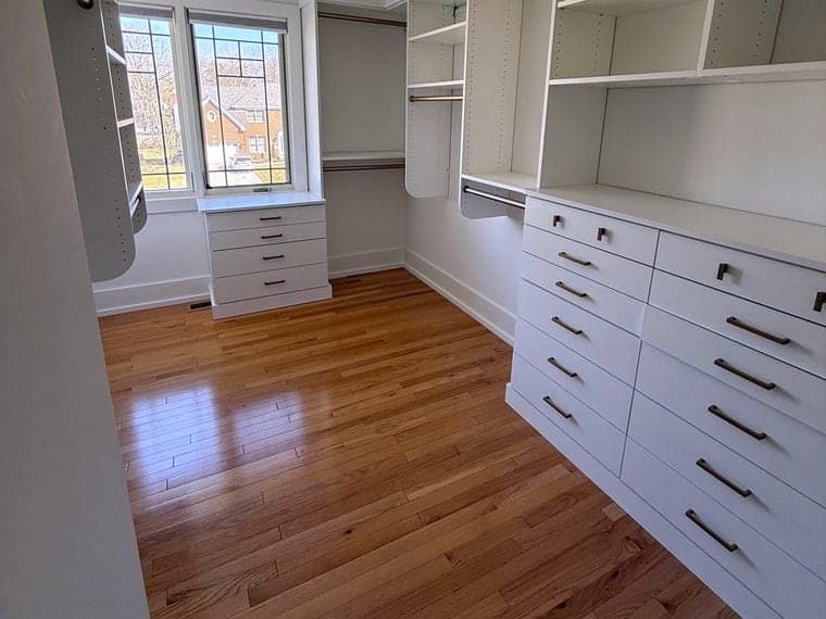 Empty walk-in closet with bare shelving and a polished hardwood floor after a DSM Cleaning Solutions move-out clean